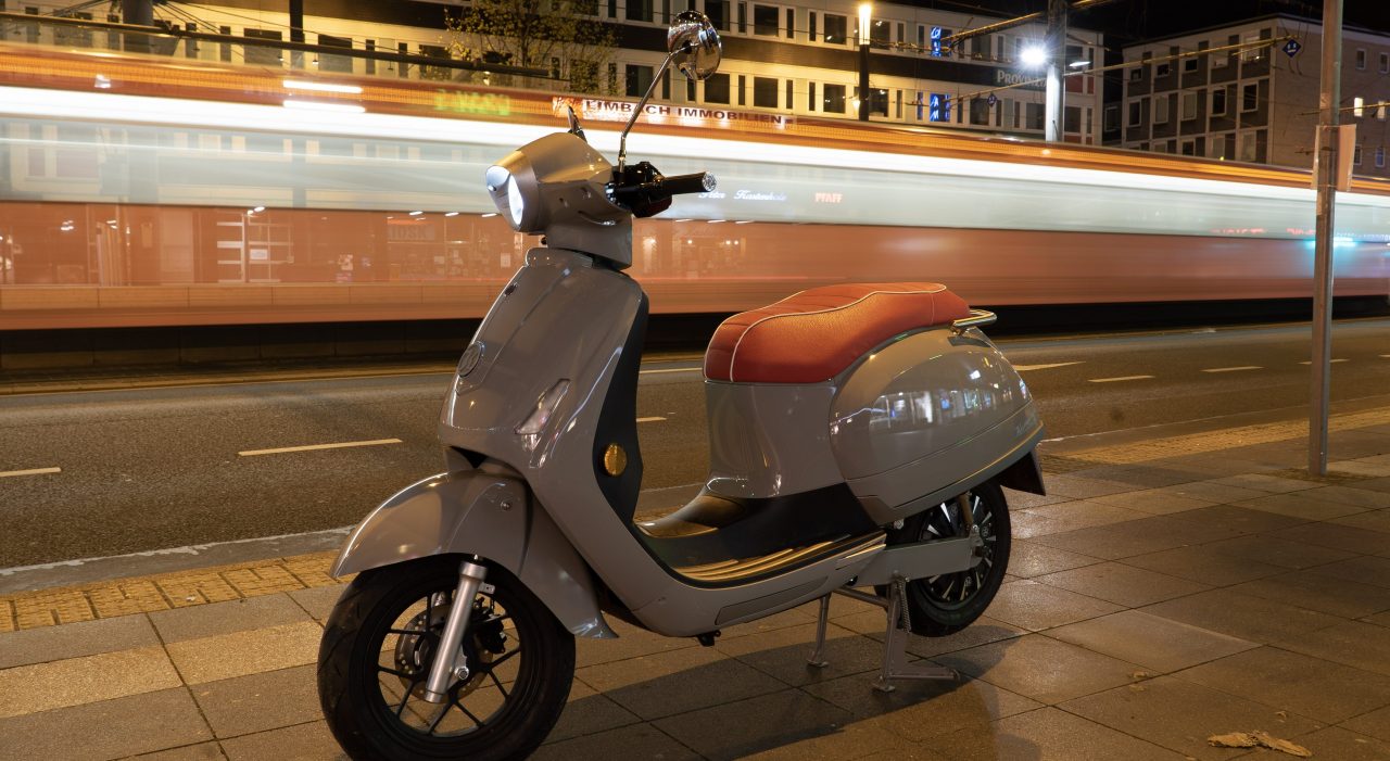 E-Roller von Kumpan electric mit Versicherungs-Schutz der Zurichbei Nacht in der Stadt